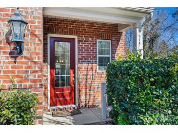 Inviting red front door with glass panels, flanked by lush greenery and a brick facade at 615 Bourton House Dr, Charlotte, NC 28211