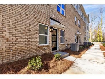 Brick townhouse featuring a front entry door with a minimalist landscaped yard at 3808 Odom Way, Charlotte, NC 28216