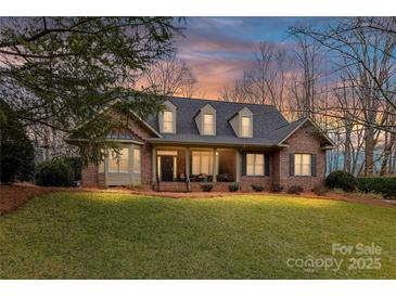 Inviting brick home with a well-manicured lawn and covered front porch perfect for relaxing evenings at 1017 Patrick Johnston Ln, Davidson, NC 28036