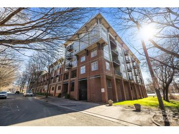Beautiful low-angle shot of a brick condo building with balconies and a lush lawn on a sunny day at 1101 W 1St St # 124, Charlotte, NC 28202
