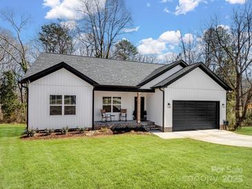 Charming, modern farmhouse with white siding, black trim, a front porch, and an attached garage at 619 Berkshire Dr, Statesville, NC 28677