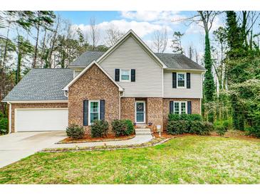 Charming two-story home with a brick facade, green lawn, and beautiful landscaping at 7921 Altacrest Dr, Concord, NC 28027