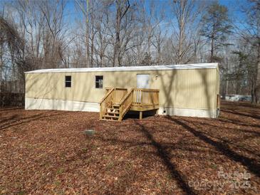 Exterior elevation of mobile home with a wooden deck and siding, nestled among trees and foliage at 335 Lake Landing Dr, Salisbury, NC 28146