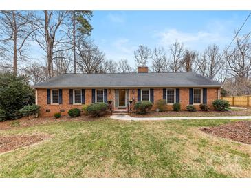 Charming brick home featuring a well-manicured lawn, mature trees, and classic blue shutters at 410 Deerwood Dr, Gastonia, NC 28054