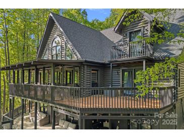 Log home with a large deck, balcony, and many windows surrounded by lush green trees at 106 Mcnaron Ln, Mooresville, NC 28117
