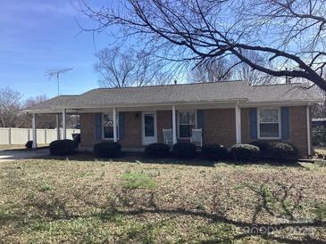 Charming single-story brick home with covered front porch, rocking chairs and manicured shrubs at 2883 Westfield Nw Ave, Concord, NC 28027