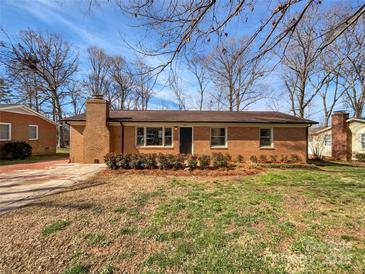 Charming brick home featuring mature landscaping and a classic chimney, set under a blue sky at 207 Bright Ave, Bessemer City, NC 28016