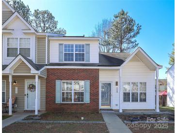Charming two-story townhome featuring brick accents, white siding, and blue shutters. The front door features a spring themed wreath at 7725 Petrea Ln, Charlotte, NC 28227