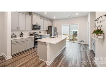 Modern kitchen with stainless steel appliances, a large island, and sliding doors to the patio at 4548 Millennium Ave, Charlotte, NC 28217