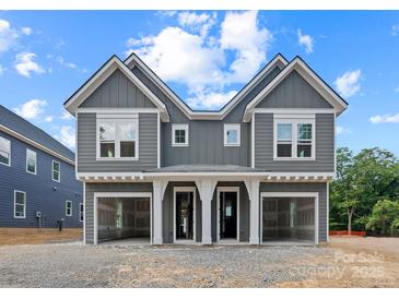 Modern townhouse featuring a gray exterior, white trim, and attached garages under a cloudy sky at 507 Bowman Rd, Charlotte, NC 28217