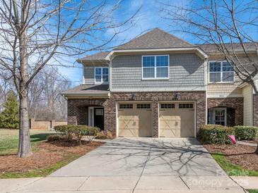 Charming townhouse exterior features brick and gray shingle facade, complemented by a two-car garage and a spacious driveway at 8418 Loxton Cir, Charlotte, NC 28214