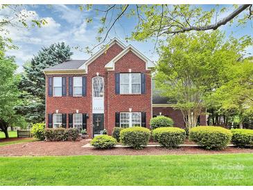 Charming two-story red brick home featuring a well-manicured lawn and established landscaping at 2217 Heath Lake Dr, Mint Hill, NC 28227