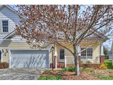 Charming yellow home featuring an attached garage, front porch, and mature tree in a well-maintained yard at 1131 Curry Way # 69, Matthews, NC 28104