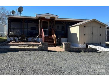 Charming home featuring a screened in porch, a brick pathway and a storage shed at 114 Dove Ln, New London, NC 28127