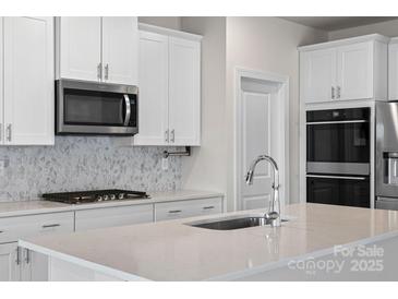 Modern kitchen with stainless steel appliances, white cabinetry, and a stylish tile backsplash at 3012 Seville St, Charlotte, NC 28214