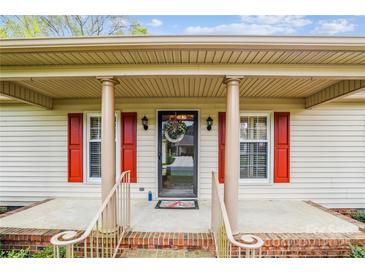 Charming home entrance featuring a covered porch with red shutters and decorative wreath on the front door at 1007 Wentworth Dr, Kannapolis, NC 28081