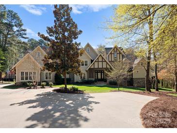 Stately home with a manicured lawn, circular driveway, and beautiful landscaping under a bright blue sky at 13215 Claysparrow Rd, Charlotte, NC 28278