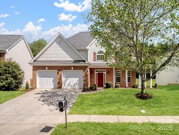 Charming two-story home featuring a manicured lawn, two-car garage and a classic brick and siding facade at 10032 Montrose Nw Dr, Charlotte, NC 28269
