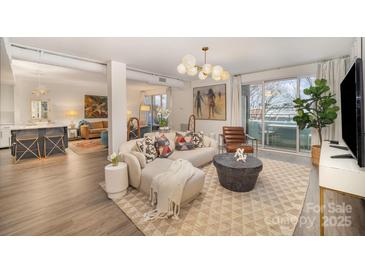 Bright living room featuring stylish furniture, modern lighting, and a sliding glass door to a private balcony at 1300 Reece Rd # 200, Charlotte, NC 28209