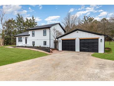 Beautifully renovated home with a two-car garage, brick driveway, black trim and a well-manicured lawn at 1498 Oakridge Farm Hwy, Mooresville, NC 28115