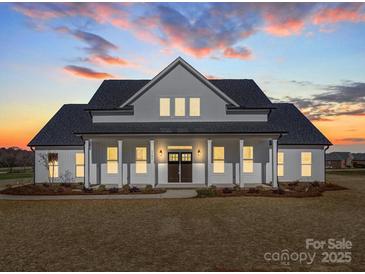 Stunning two-story home with a welcoming front porch and eye-catching architectural details at dusk at 1706 Ruben Rd, Monroe, NC 28112