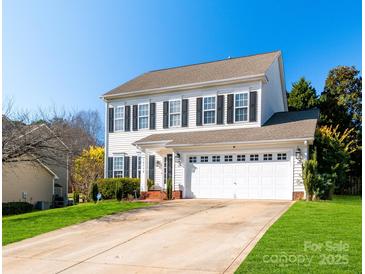 Charming two-story home featuring a well-manicured lawn, attached two-car garage, and classic black shutters at 12112 Autumn Winds Ln, Pineville, NC 28134