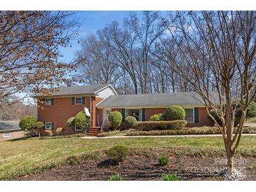 Charming brick home featuring mature landscaping and a well-manicured front lawn at 211 Kingsway Cir, Charlotte, NC 28214