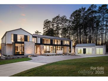 Stunning modern home with clean lines, large windows, and a stone facade offers sophisticated curb appeal at 2536 Brawley School Rd, Mooresville, NC 28117