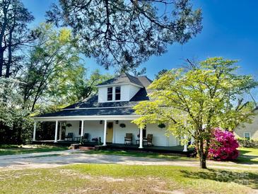 Charming white home with a full front porch, rocking chairs, and mature trees at 415 E Richland St, Kershaw, SC 29067
