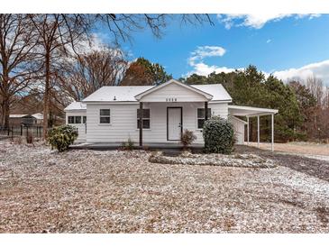 Charming white home featuring a covered carport, front porch, and landscaped yard dusted with snow at 5028 Wilgrove Mint Hill Rd, Mint Hill, NC 28227