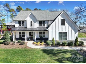 Beautiful two-story home with white siding, black trim, a manicured lawn and professional landscaping at 16709 Mckee Rd, Charlotte, NC 28278
