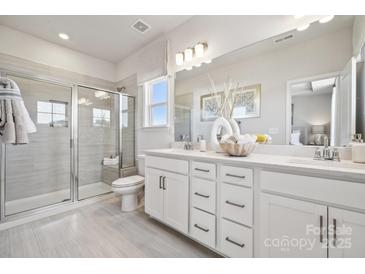 Modern bathroom features a glass shower, double vanity, and neutral tile flooring at 3218 Stelfox St, Charlotte, NC 28262