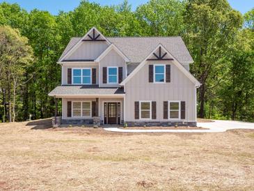 Charming two-story home featuring gray siding, brown shutters, and a well-manicured lawn and a backyard forest at 5311 Meadowland Pkwy, Monroe, NC 28112