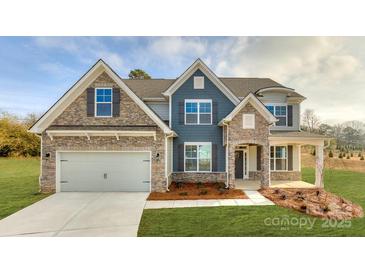 Beautiful two-story home featuring a stone facade, blue accents, a two-car garage, and manicured lawn at 7033 Sylvan Retreat Dr, Denver, NC 28037