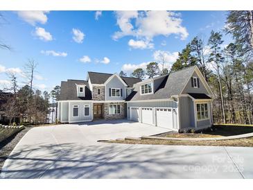 Beautiful exterior view of a light blue two-story home with three-car garage and a long concrete driveway at 154 Fox Hunt Dr, Mooresville, NC 28117