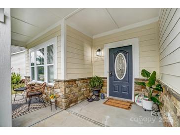 Charming front porch with stone accents, seating, and a stylish front door at 5006 Sand Trap Ct # 142, Monroe, NC 28112