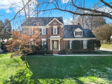 Charming two-story brick home with manicured lawn and mature trees at 1427 Matthews Plantation Dr, Matthews, NC 28105