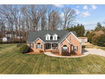 Charming brick home featuring a manicured lawn, complemented by mature trees and inviting curb appeal at 150 Canopy Oak Ln, Statesville, NC 28625