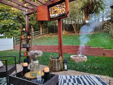 Relaxing backyard area featuring a patio, pergola with TV, and a cozy fire pit, perfect for outdoor entertaining at 7028 Lowen Rd, Charlotte, NC 28269