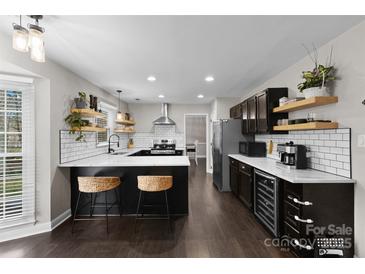 Modern kitchen featuring dark cabinets, a large island with seating, and stainless steel appliances at 7201 Brassy Creek Ln, Charlotte, NC 28269