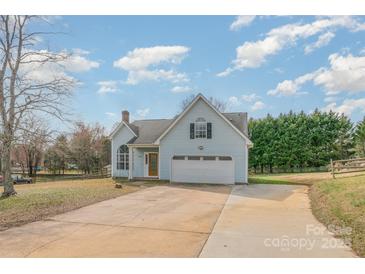 Charming home featuring a well-manicured lawn, attached garage, and long private driveway at 8552 Indian Summer Trl, Harrisburg, NC 28075