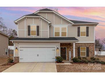 Charming two-story home showcasing a brick and siding facade, complemented by a two-car garage and manicured landscaping at 920 Clementine Rd, Monroe, NC 28110