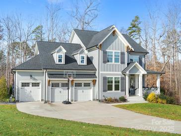 Charming two-story home boasts a three-car garage, inviting front porch, and well-manicured lawn at 2127 Nims Village Dr, Fort Mill, SC 29715