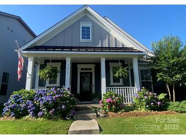 Charming home featuring a cozy front porch with lush landscaping and a well-maintained lawn at 7035 Walnut Branch Ln, Charlotte, NC 28277