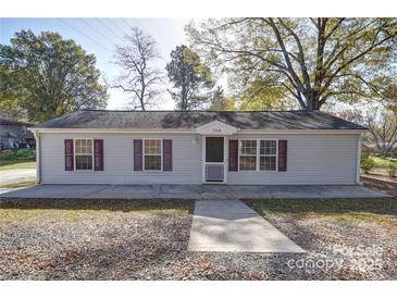 Charming single-story home featuring light gray siding, a dark roof, and red window shutters at 709 High St, Albemarle, NC 28001