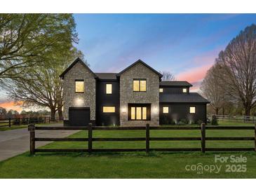 Stunning two-story home with stone and black brick exterior, a manicured lawn, and a charming wooden fence at 1575 Shinnville Rd, Cleveland, NC 27013