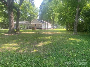 Charming single-story home with a covered carport and a well-maintained, spacious front yard surrounded by mature trees at 28419 Nc Hwy 73 Hwy, Albemarle, NC 28001