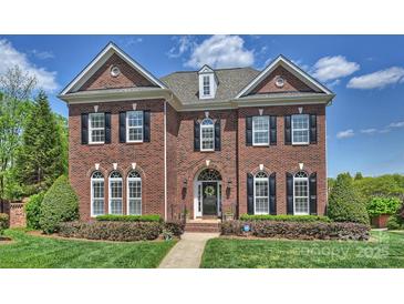 Elegant brick home featuring a manicured lawn, symmetrical design, and black shutters under a partly cloudy sky at 100 Cliveden Ct, Belmont, NC 28012