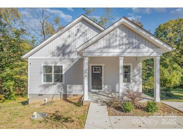 Charming home featuring a covered front porch with white columns and vertical siding at 1006 W B St, Kannapolis, NC 28081