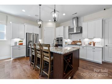 A spacious kitchen featuring white cabinetry, stainless steel appliances, a large island, and modern pendant lighting at 126 Goorawing Ln, Mooresville, NC 28115